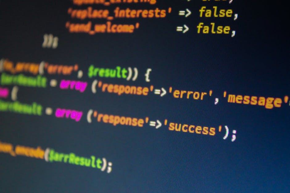Photograph of a computer screen displaying lines of HTML code in a dark-themed coding environment. The code includes tags such as <section>, <div>, <h3>, and <p>, with text written in multiple languag